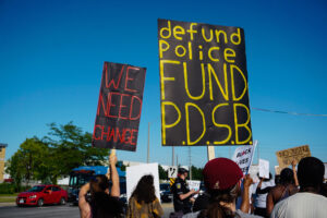 defund the police banners held at black lives matter protest